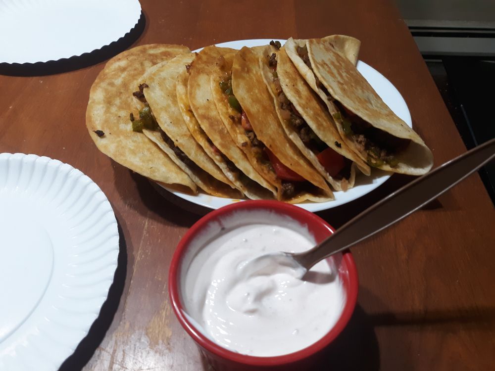 a plate of 6 quesadilla-taco hybrids with sour cream on the side
