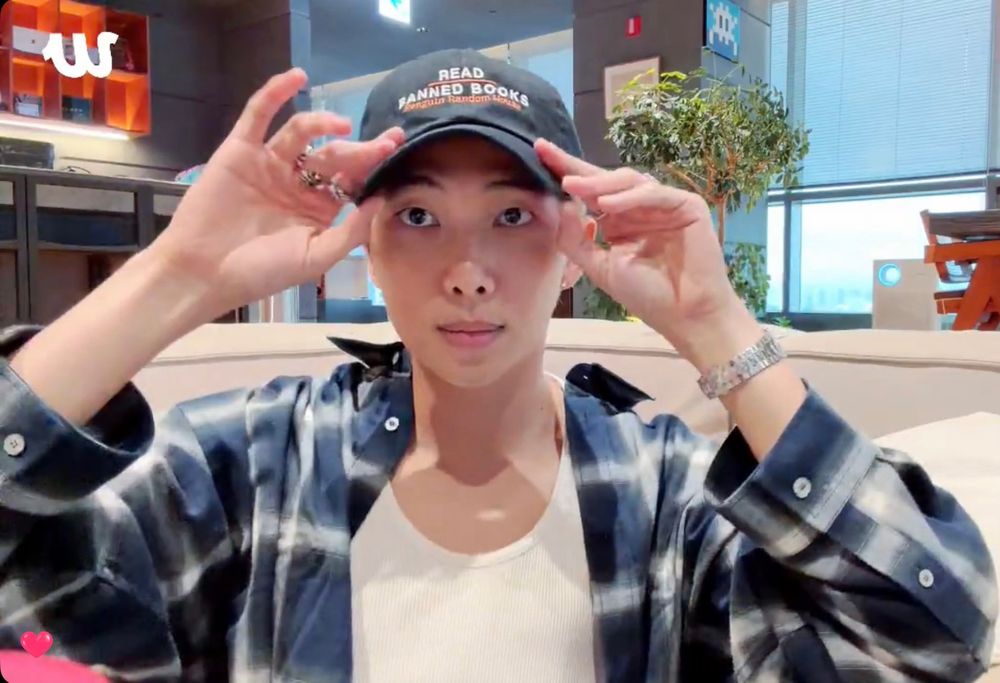 BTS member RM wearing a dark "Read Banned Books - Penguin Random House" hat.