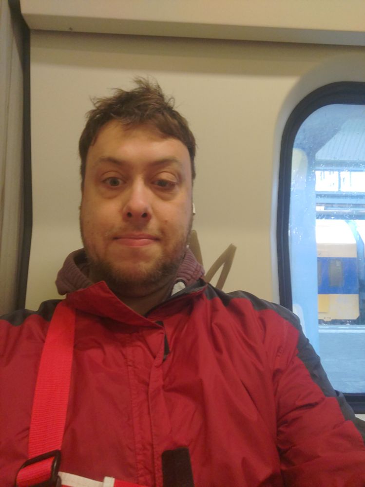 Ik zit in de trein met een rode jas aan