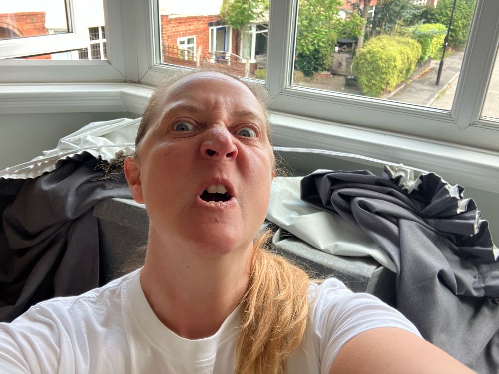 Me looking angry in front of the curtain rail with grey curtains on collapsed u see the window