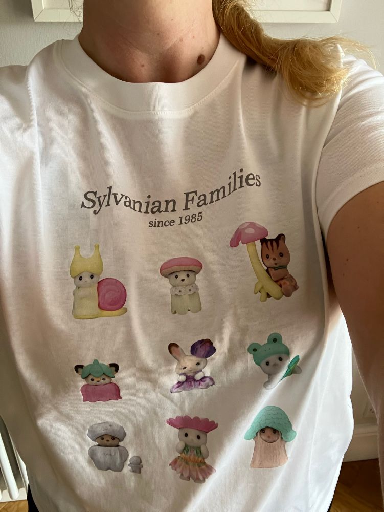 My in a white T-shirt with sylvanian families at the top and a 3 x 3 grid of cute lil characters 