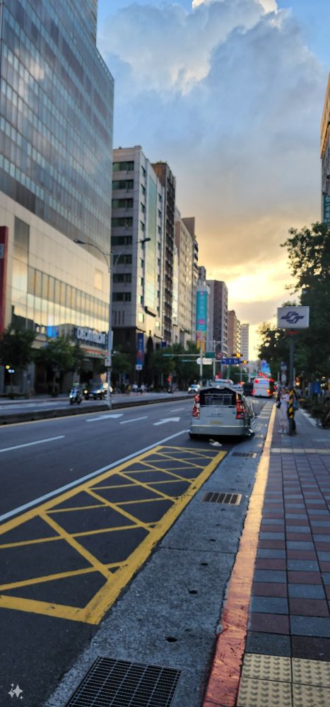 A sunset on a long street, with a parked car