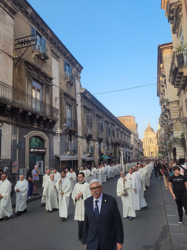 Viele Mönche in weißen Gewändern in einer Prozession. Am Ende der Straße der Dom. 