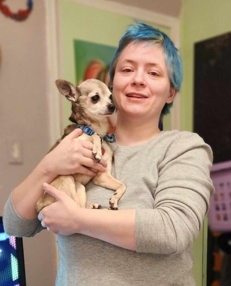 A dude holding a tiny, 10 year old Chihuahua 