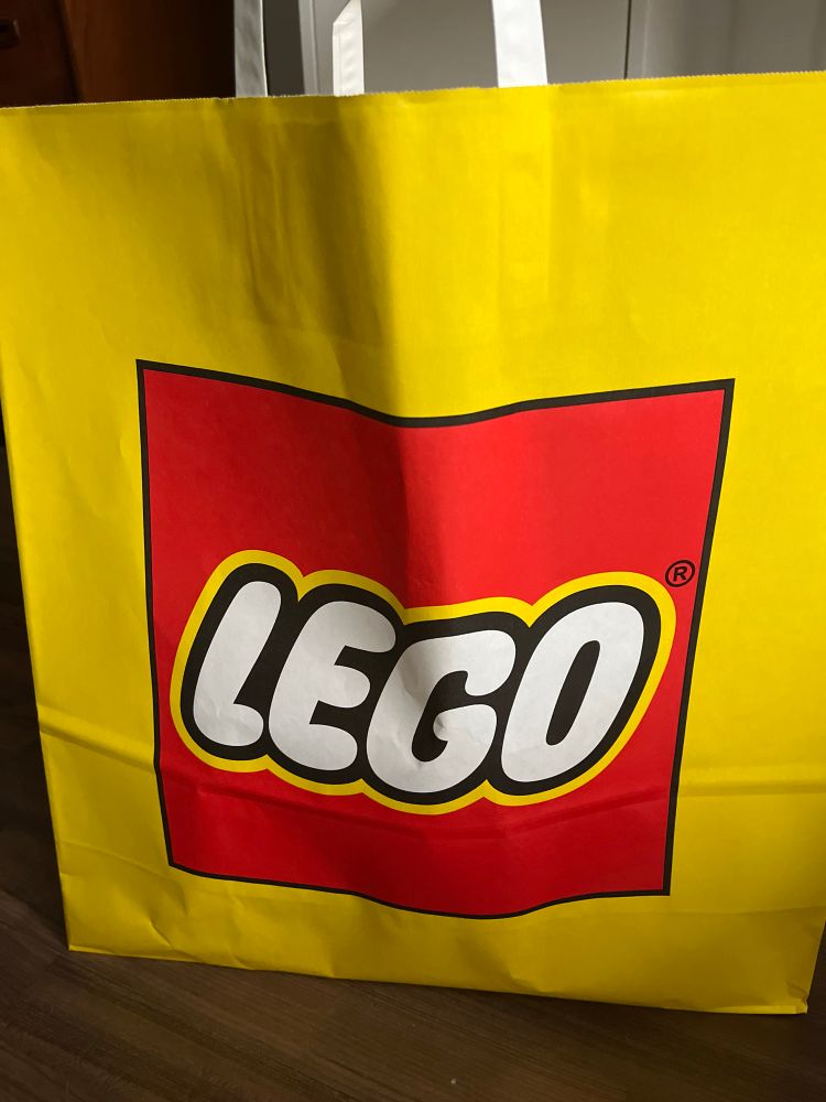 Eine große gelbe Tüte mit rot-weißem Lego-Logo