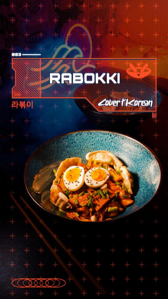 A futuristic-looking food photo in a Cyberpunk aesthetic showing a bowl of Rabokki (Korean tteokbokki with instant ramen) in the front and colorful LED lighting in the back.