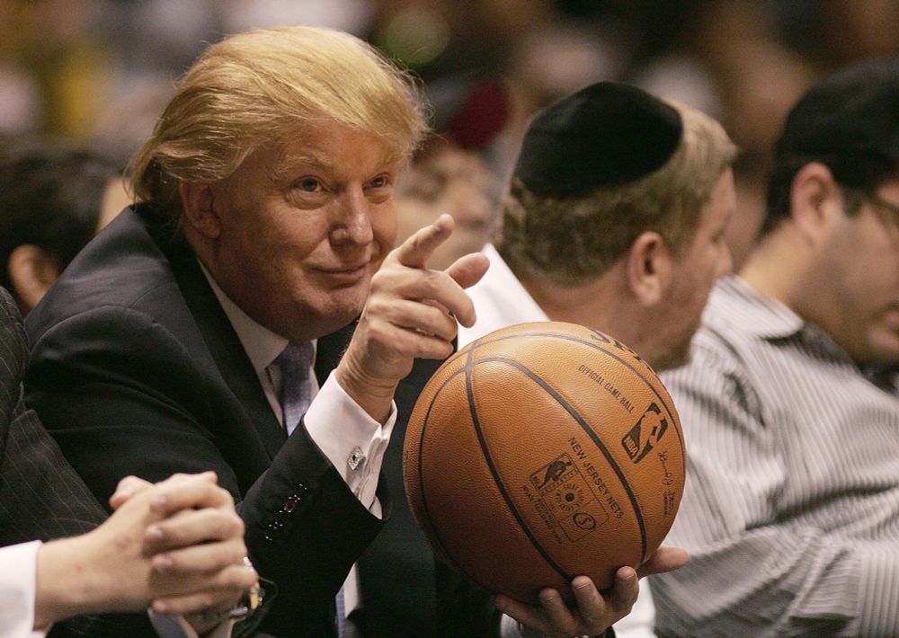 Donald Trump holding a basketball, making a smug face, and pointing 