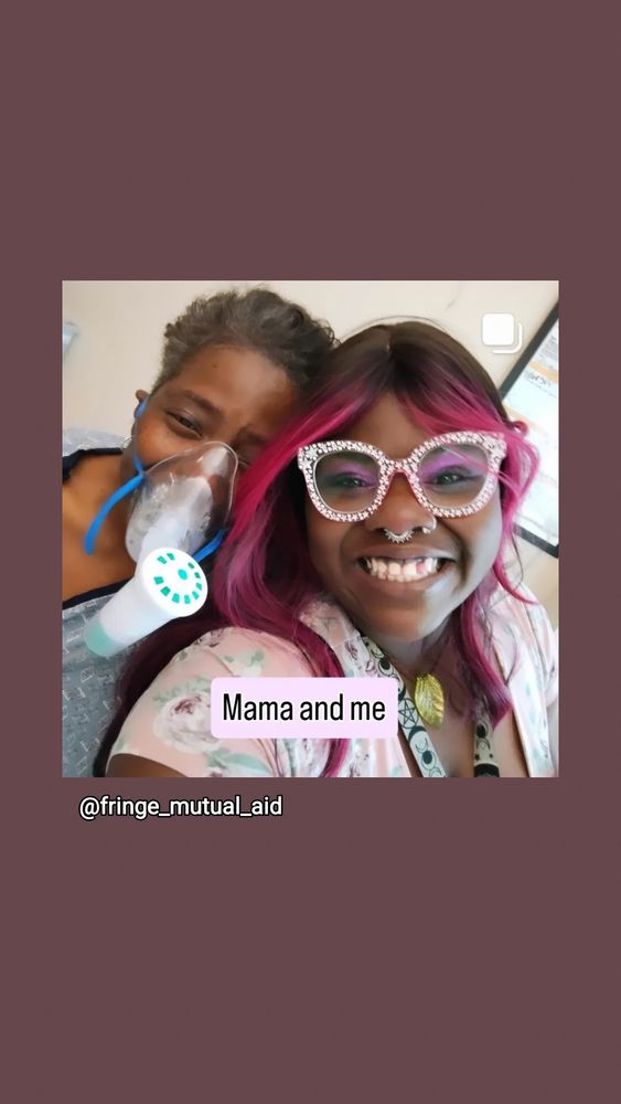 Black woman in hospital again and respirator poses with her daughter. A black girl in pink sparkly glasses. They are both smiling.