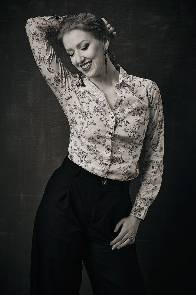 Black and white photo of Sonia Harcourt in studio with a gorgeous smile. What could she be thinking of?