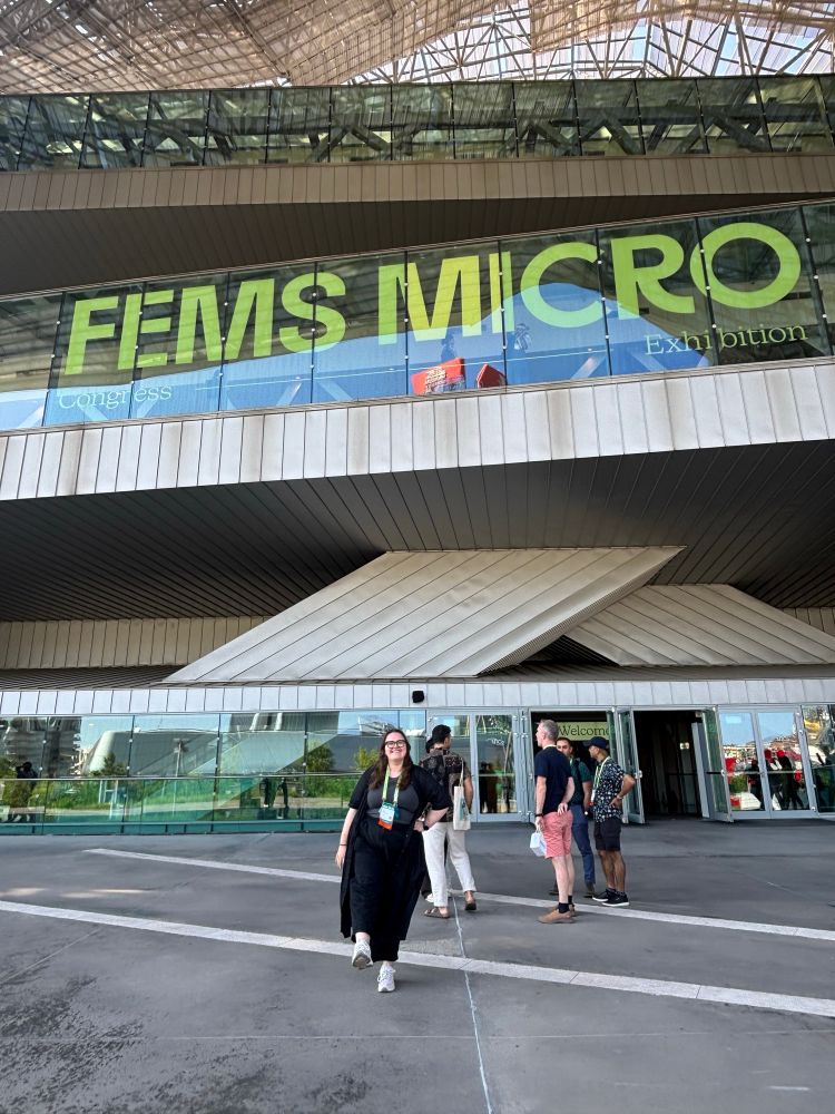 Me standing in front of the FEMS sign. I'm kicking a leg forward and smiling widely 