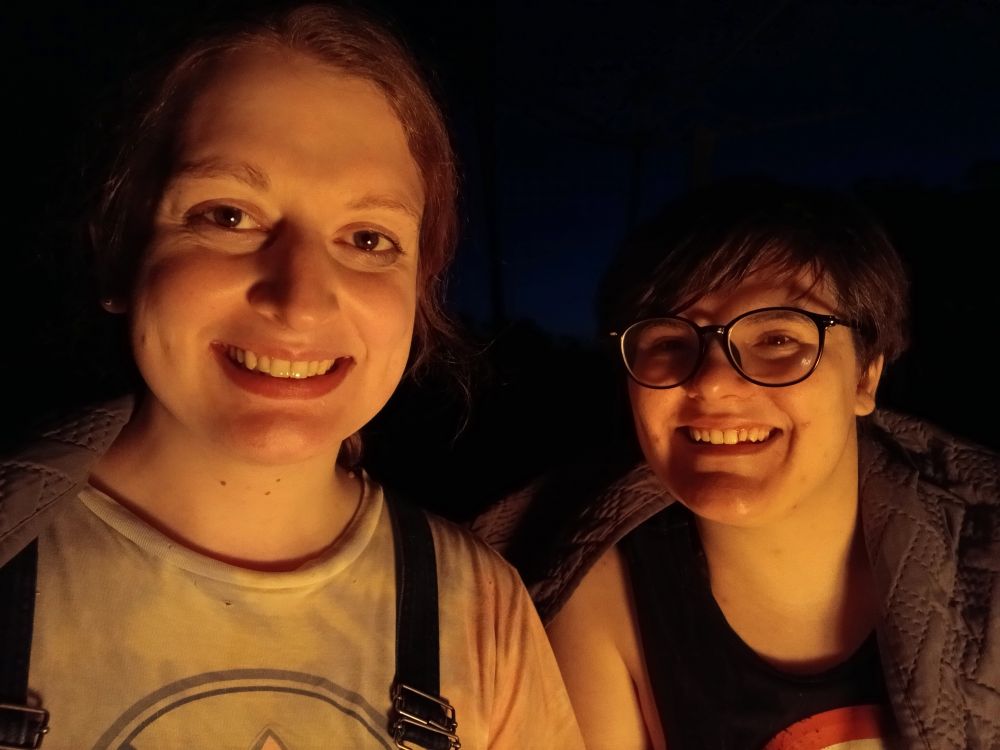 my spouse and I sitting outside on the ground with a blanket draped over our shoulders.