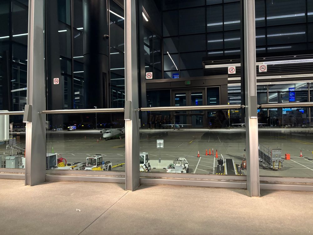 Outdoor patio with tall glass walls overlooking an airport ramp.