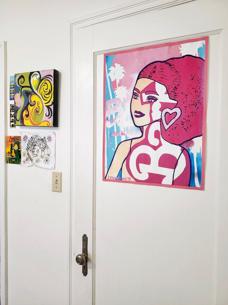 A few pieces of artwork on a wall / door. 

One small colorful piece by Sole Fiumefreddo and a large pink/blue piece of Barbie by Zsorryon