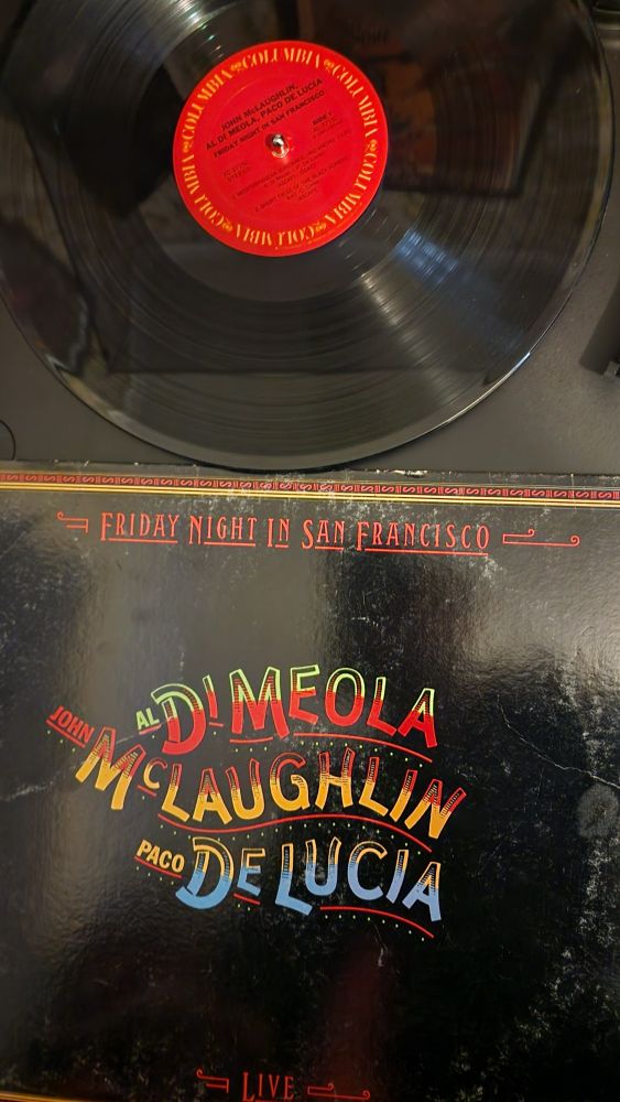 The vinyl and cover for the album Friday Night in San Francisco by Al DiMeola, John McLaughlin, and Paco DeLucia.