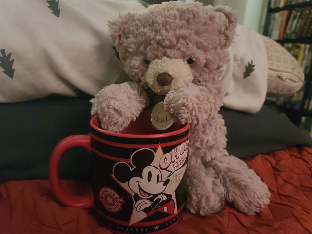 A teddy bear with a Mickey Mouse coffee cup 
