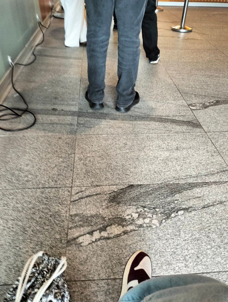 Plattenfussboden mit 3 paar Beinen, welche sehr eng zusammen stehn.
Plus meine Tasche und mein rechter Fuss unten im Bild.