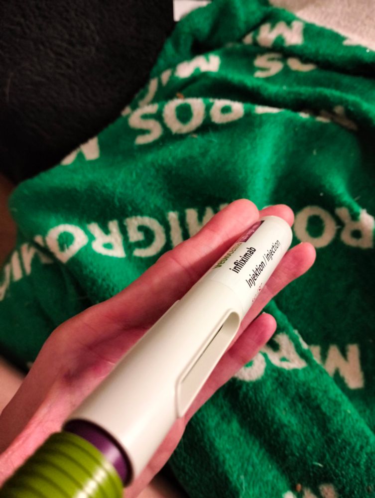 Eine Hand hält eine gebrauchte Simultanspritze im dem Wirkstoff Infliximab drin.