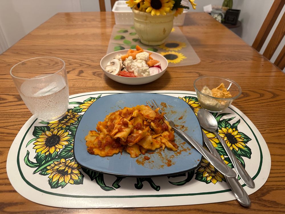 Assiette de raviolis à la courge musquée accompagnée d’un bol de crudités et de deux hummus. 