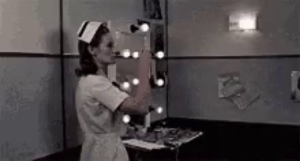 a nurse is standing in front of a mirror .