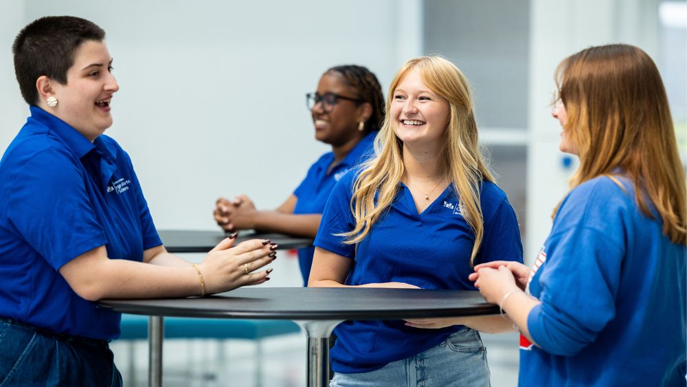 Students standing at a table and chatting.
