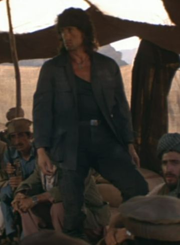 Sylvester Stallone in Rambo 3 wearing, like, a canvas jacket, an undershirt with the collar all the way down at his pecs, and some kind of black belted slacks. I don't know fashion terminology, apologies.