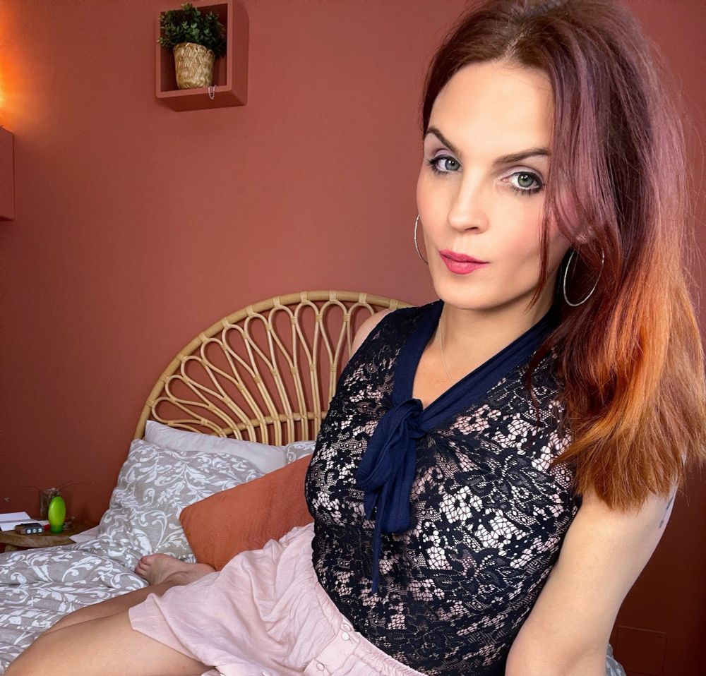 woman on bed red hair blue lace top pink skirt