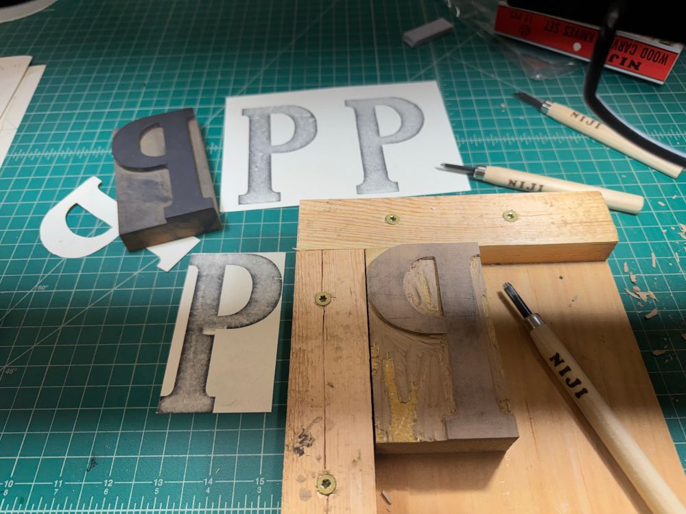 Image of a linoleum block carving jig, making a copy of the capital letter P for a wood type poster. 