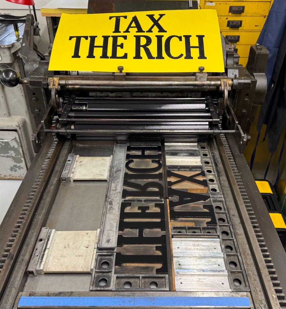 Placard on press: “Tax the Rich”