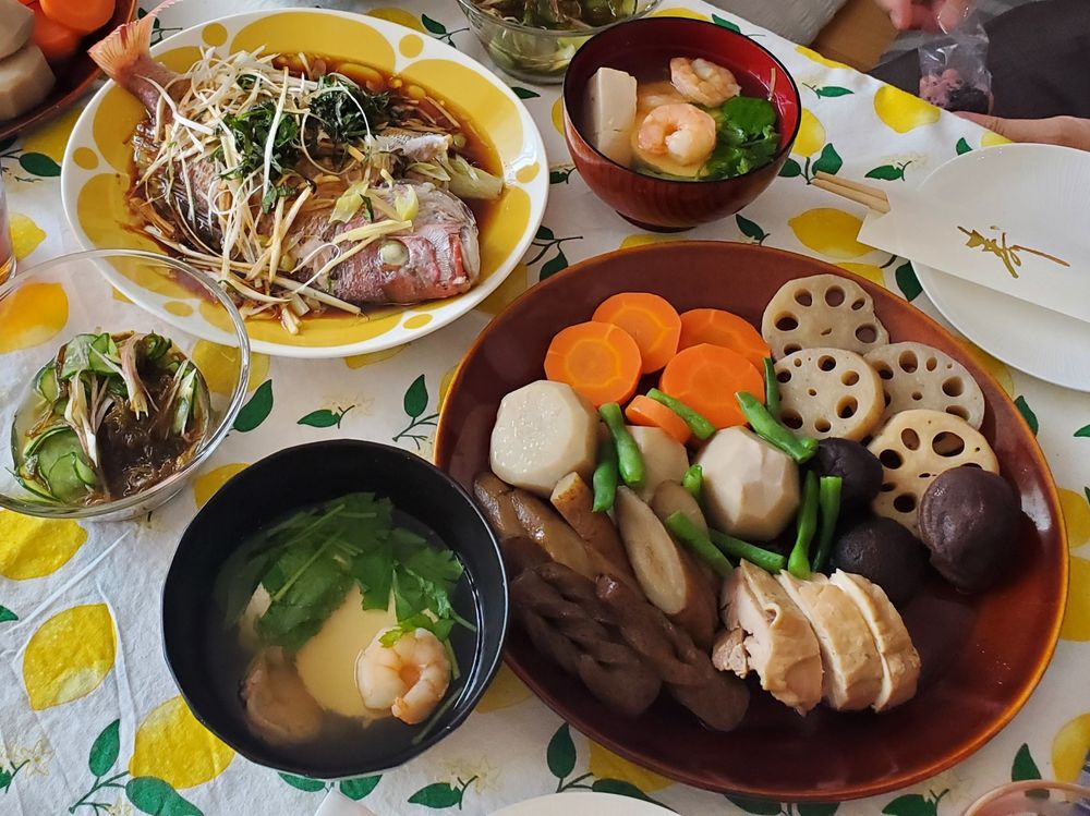 お祝いの食卓写真。煮しめ、ちこ鯛の清蒸魚、海老と豆腐のお吸い物、きゅうりの酢の物。