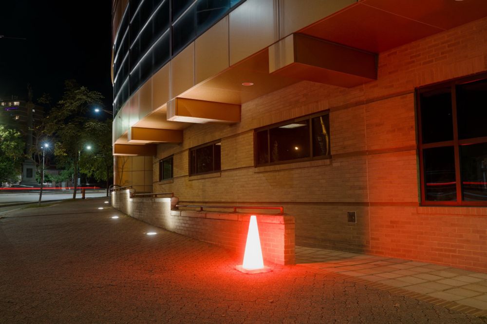An illuminated cone outside a curved building at night. 