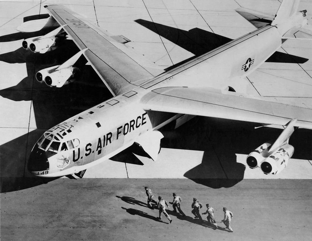 A black and white overhead photograph of the crew of a B-52 bomber running toward their aircraft during an alert drill.
