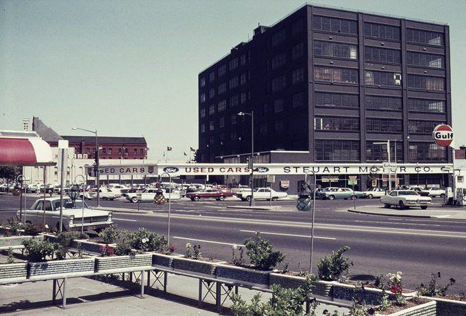 A color photograph of the mid-rise steel and glass building at Fifth and K Streets, NW, in Washington, DC, whose upper floors housed the CIA's National Photographic Interpretation Center. The building shared a block with Steuart Motor Company, a Ford dealership.