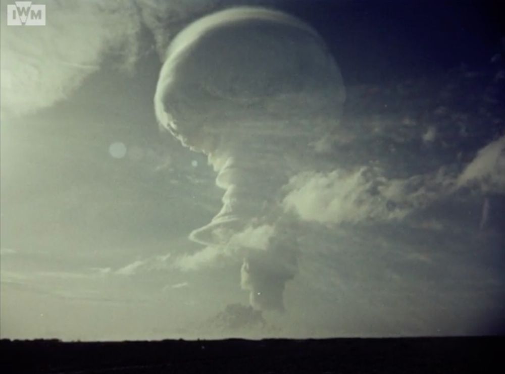 A screenshot from an official color film of the Round C test from the ground, showing its large, white ice-cream-cone-shaped mushroom cloud from the ground above Christmas Island.