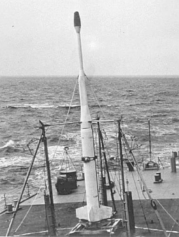 A black and white photograph of a white Lockheed X-17A rocket in firing position on the deck of the USS Norton Sound with a small dark-colored W25 warhead attached.