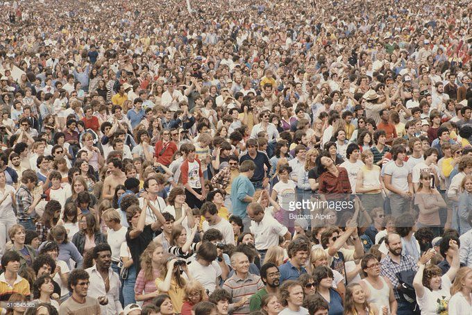 A color photograph of the some of the massive crowd at the rally on the Great Lawn in Central Park. People are facing forward, watching either a speech or a musical performance on the stage.