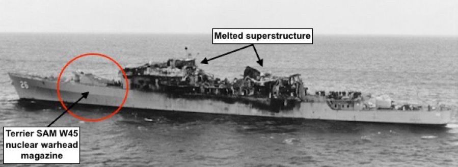 A black and white photograph showing the USS Belknap after the accident, with the location of the forward magazine for the W45 warheads for the Terrier missiles circled in red. Nearly the entire superstructure has been destroyed by the collision and melted in the resulting fire. Some sailors can be seen standing on deck on aft portion of the ship.