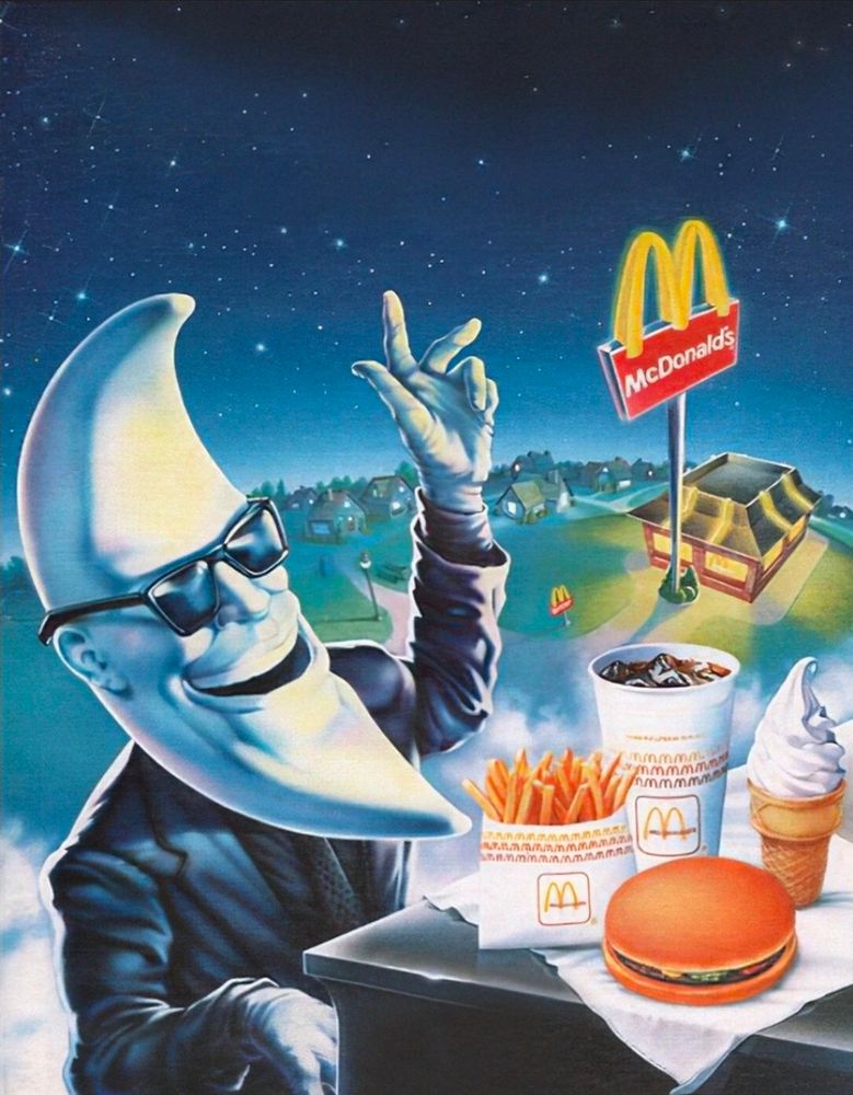 A man with a moon for a head, sits at a piano, with various McDonald's food items on top of it.