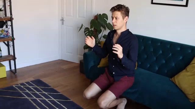 a man sits on his knees in front of a couch