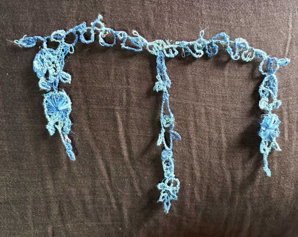 The finished lace, shades of pale blue and vaguely floral, needs a press