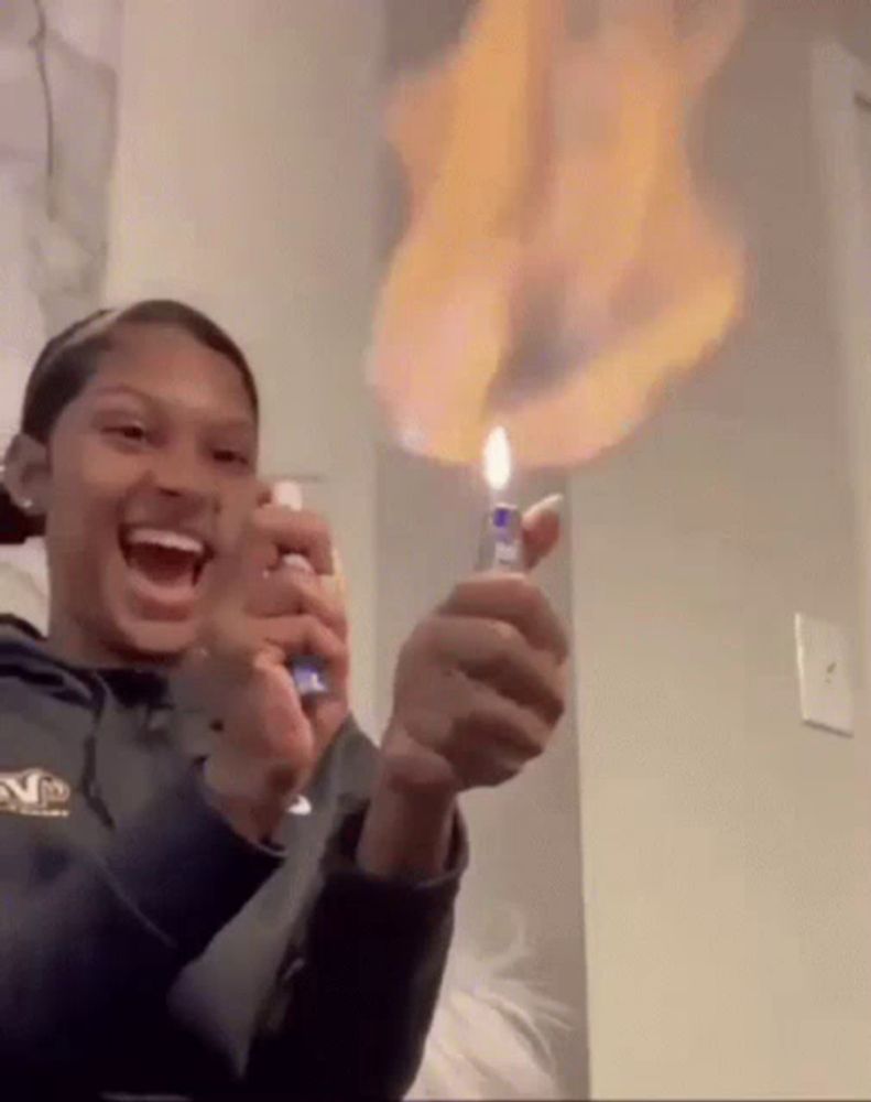 a woman is holding a lighter that is on fire .