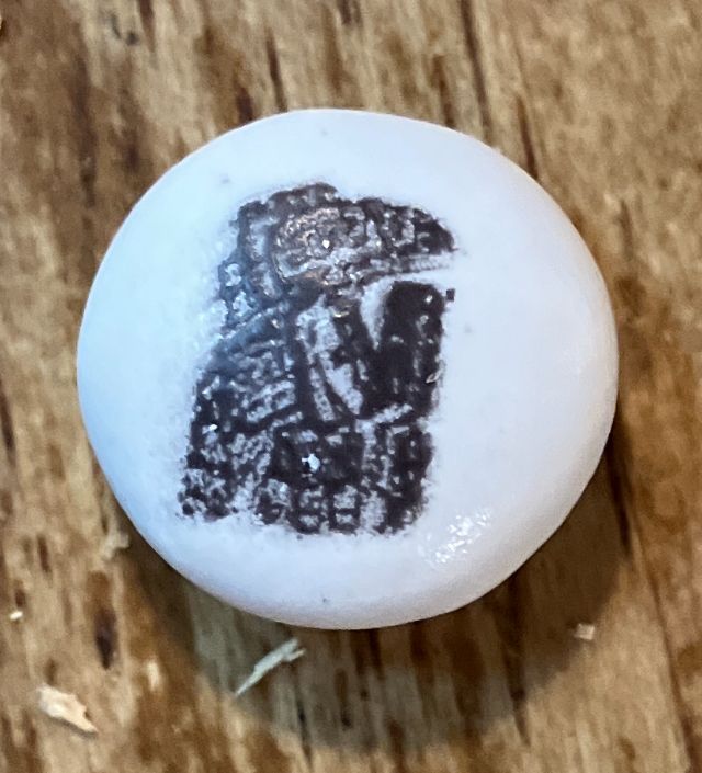 Close-up of white M&M with Alaska Native formline bird (raven?) in black. 
