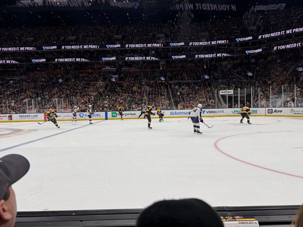 View of a Boston Bruins hockey game in progress, against the Columbus Blue Jackets. The picture is almost at ice level