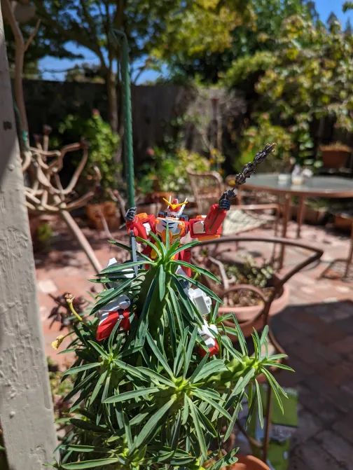 Gunpla posed confidently atop a succulent holding a sprig of lavender. 