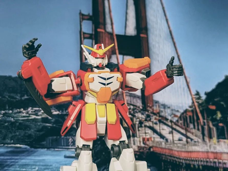 Gunpla with a photo filter, making a thumbs up, posed in front of the Golden Gate Bridge.