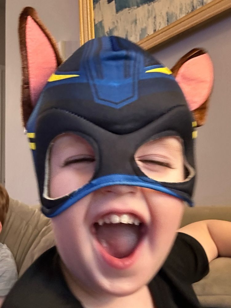 Little boy with mouth open and squinting eyes in a Paw Patrol Chase mask