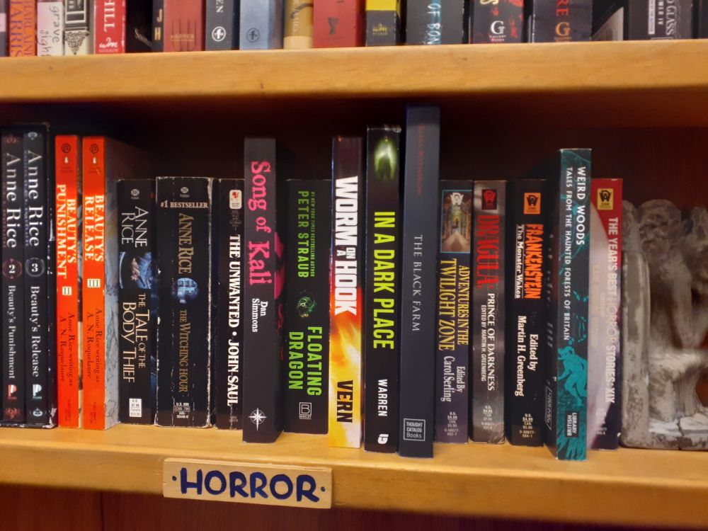 A shelf of used horror books including Worm On a Hook by Vern