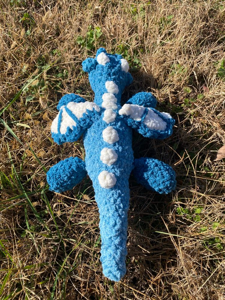 Crocheted blue dragon laying on the grass