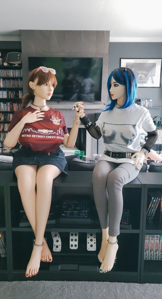 two silicone companion dolls, dyanne bailey (made by normondoll) and miss winter (made by doll sweet), are seated on a bookcase in deafening silence towers. they're about a foot apart, but they're gazing at each other and holding each other's rubbery hand. it's very sweet, and if you can't appreciate the sentiment, you are a monster. :(