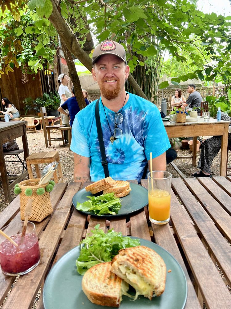 My happy friend Henry at a garden table laden with grilled sourdough sandwiches, a pineapple/ginger kombucha and fresh mulberry with soda. 