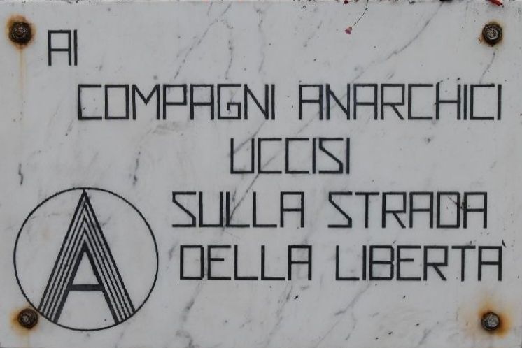 Targa di marmo in località Colonnata (Carrara) con incisa la scritta: Ai compagni anarchici uccisi sulla strada della libertà 
Incisa sulla sinistra della targa una A cerchiata